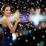 party, drinks, holidays, christmas and people concept - smiling woman in evening dress holding cocktail over night lights and snow background